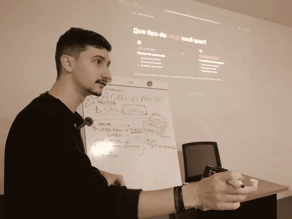Gabriel explicando para a turma, com o quadro branco rabiscado e o slide projetado atrás
