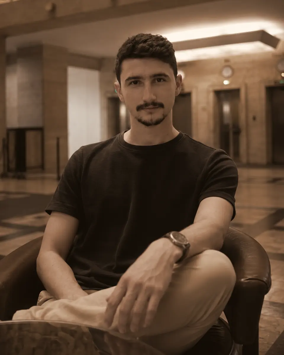 Retrato de Gabriel Pedrozo, sentado numa poltrona, camiseta preta